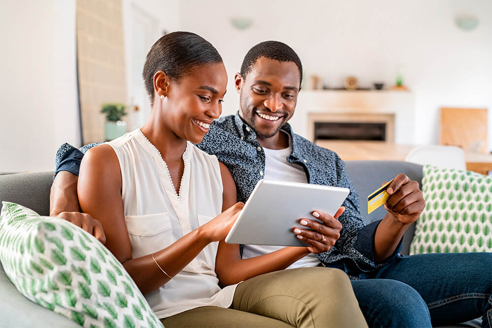casal negro fazendo compras online segurando tablet e cartão de crédito