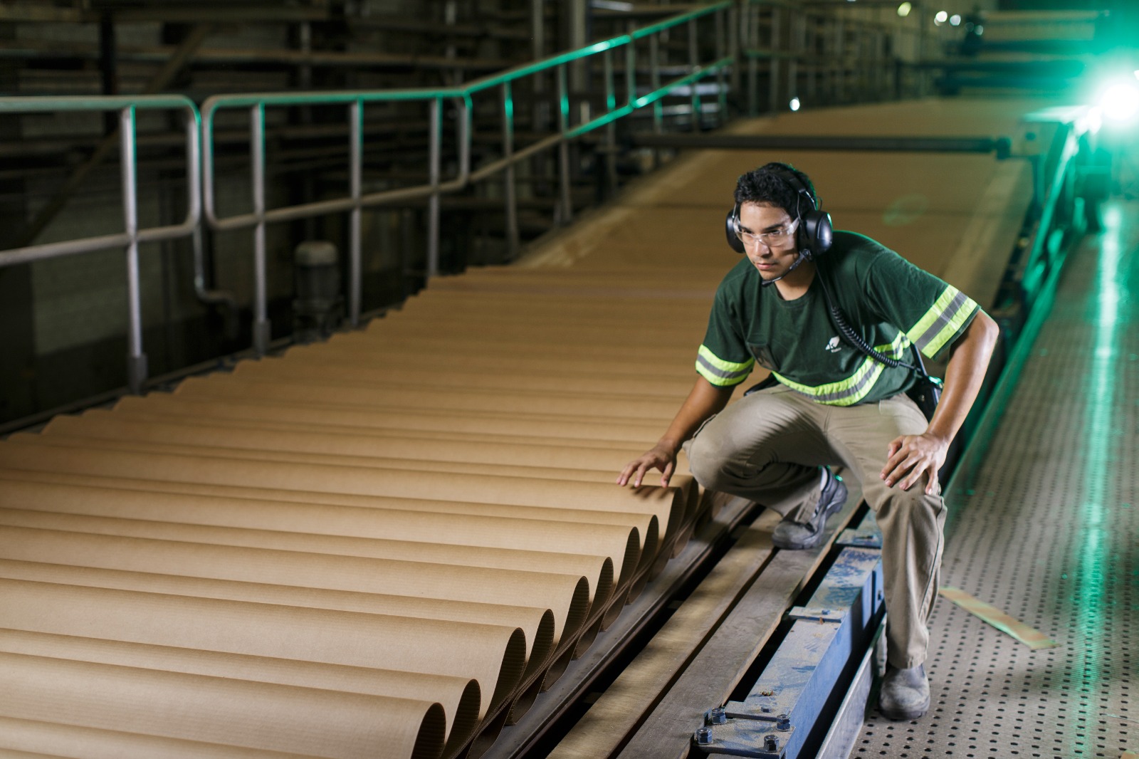 Colaborador Klabin, usando equipamentos de proteção enquanto fiscaliza uma esteira com folhas de papelão recém fabricadas