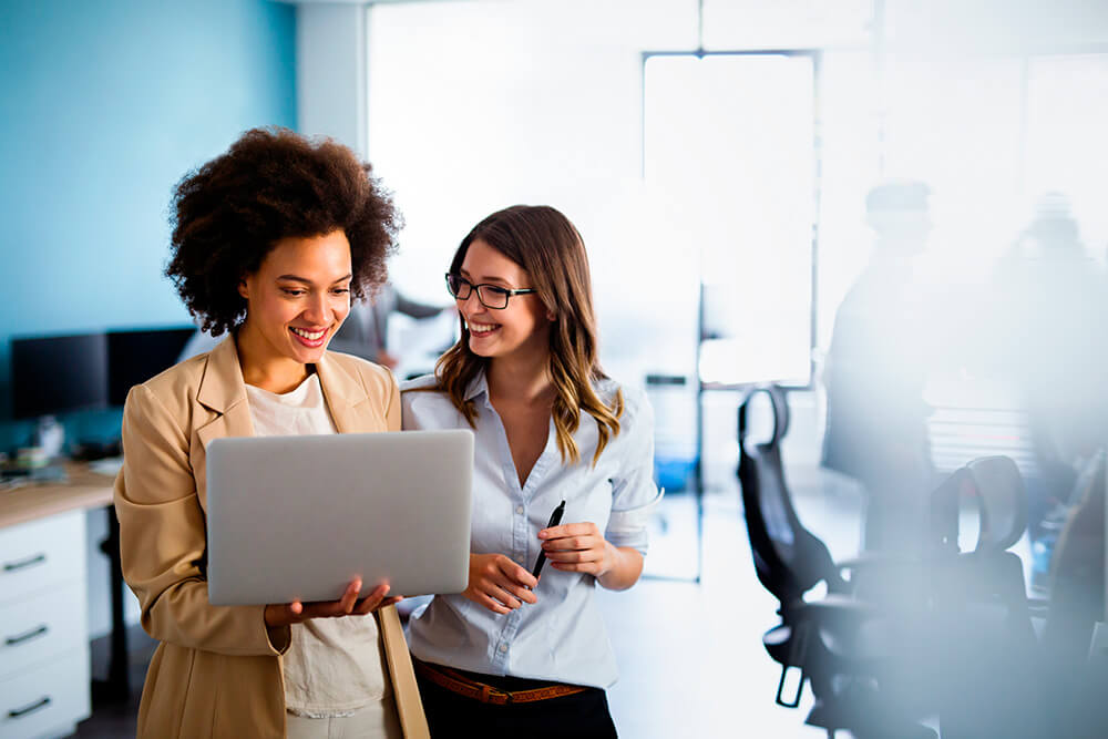 Duas mulheres de pé trabalhando com o computador