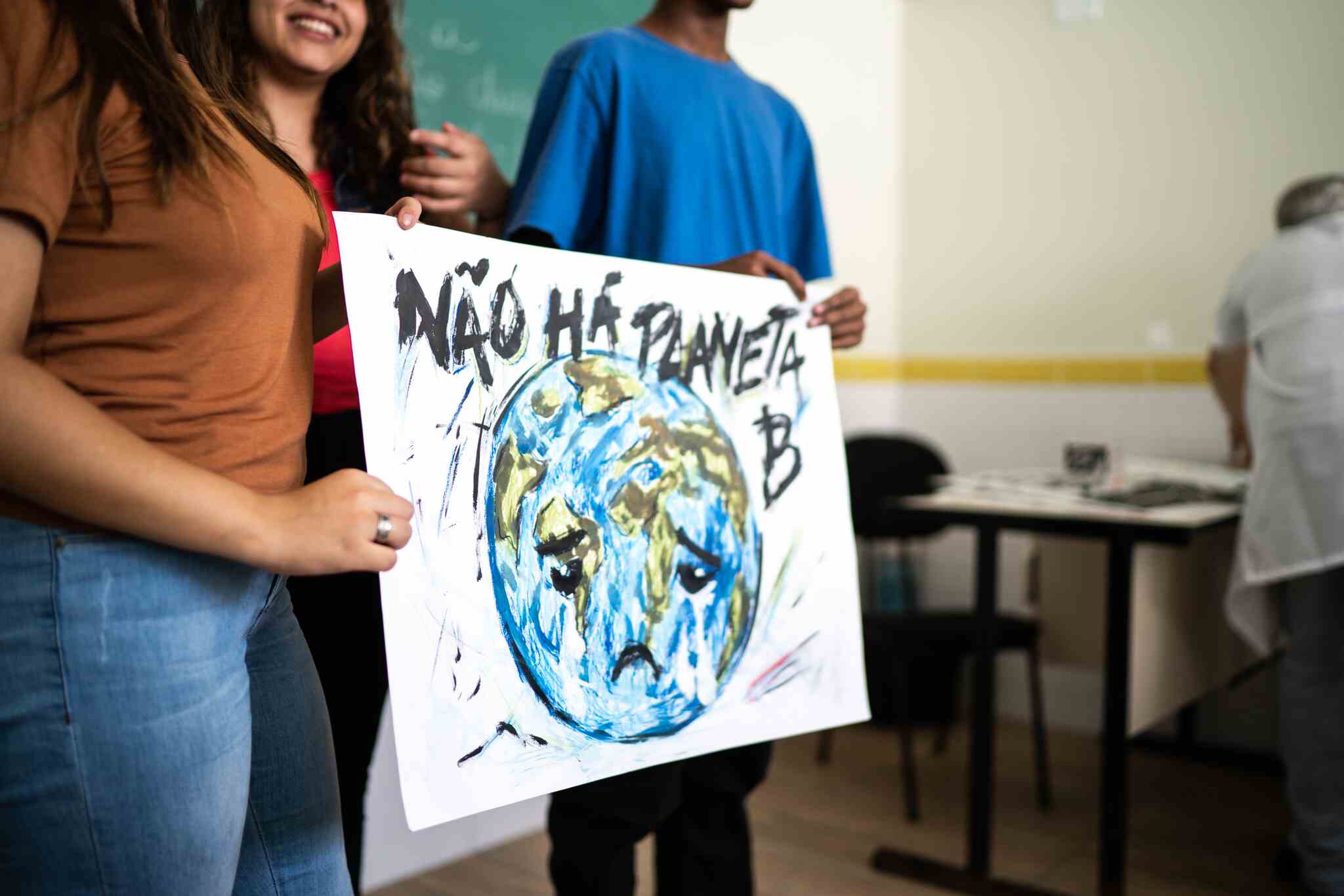 Estudantes segurando cartaz sobre educação ambiental.