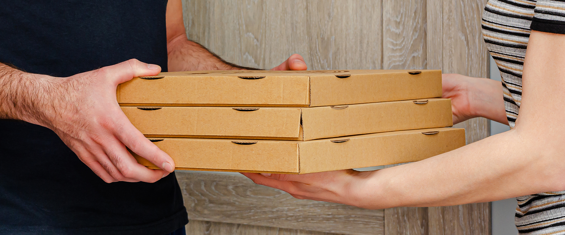 Pessoa entregando tres caixas de pizza para outra pessoa